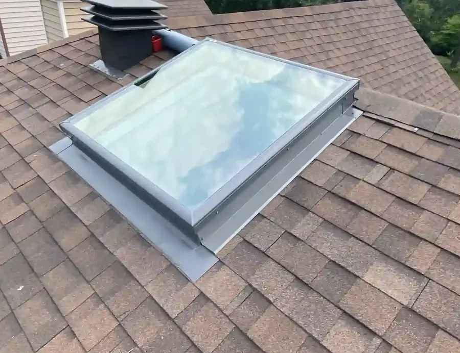 Finished skylight with metal flashing set into brown shingles